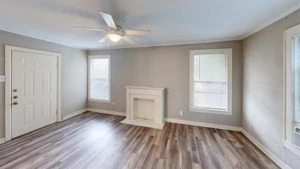 an empty room with wooden floor cabinet and windows