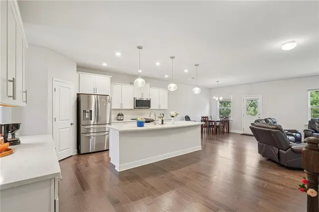 a living room with stainless steel appliances kitchen island furniture and a table