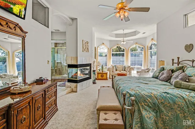 a spacious bedroom with a bed a chandelier and a large mirror on the dresser