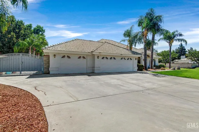 a view of a white house with a yard and palm trees