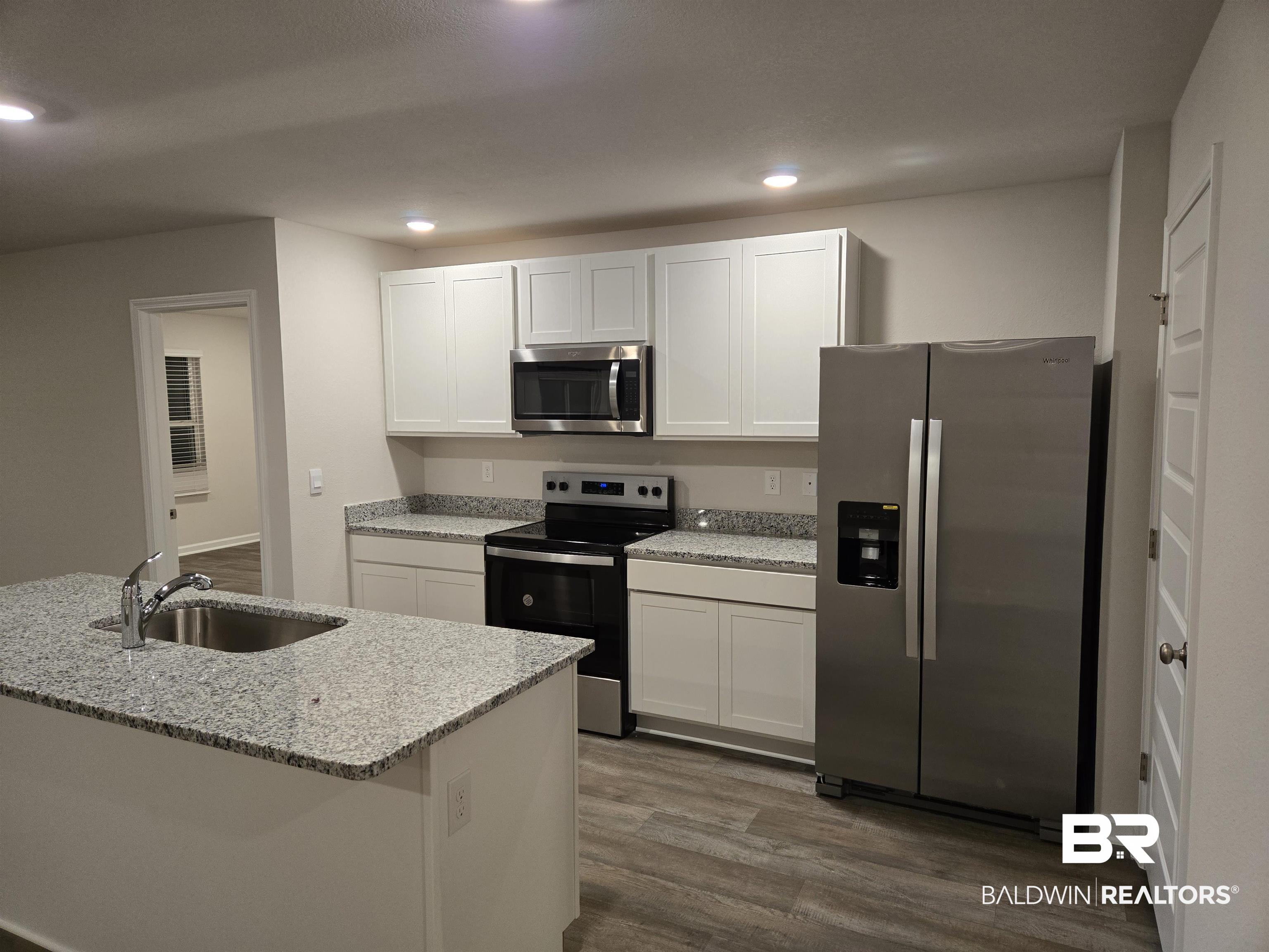 24194 Veranda Circle Elberta, AL 36530 - Photo 15 of 31 Kitchen with dark wood-type flooring, white cabinets, sink, light stone counters, and stainless steel appliances