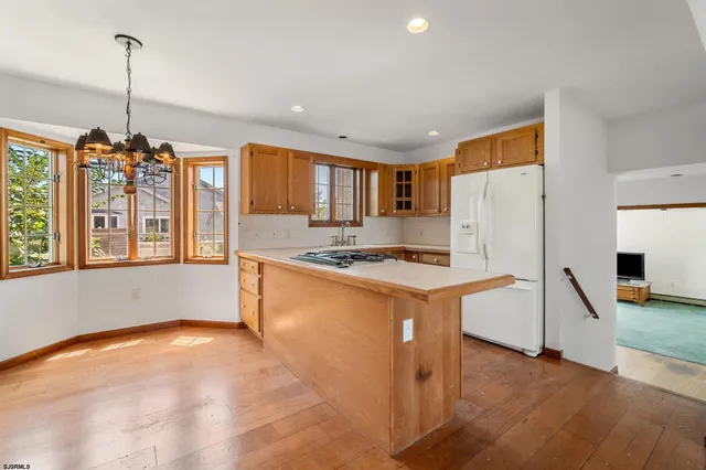 a kitchen that has a refrigerator a stove a sink and a wooden floor