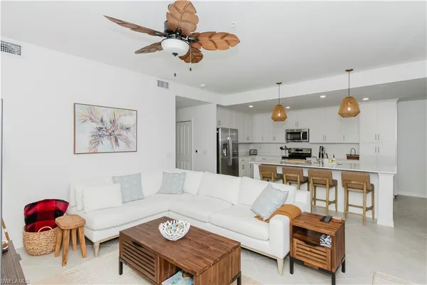 a living room with furniture kitchen view and a chandelier