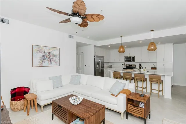 a living room with furniture kitchen view and a chandelier