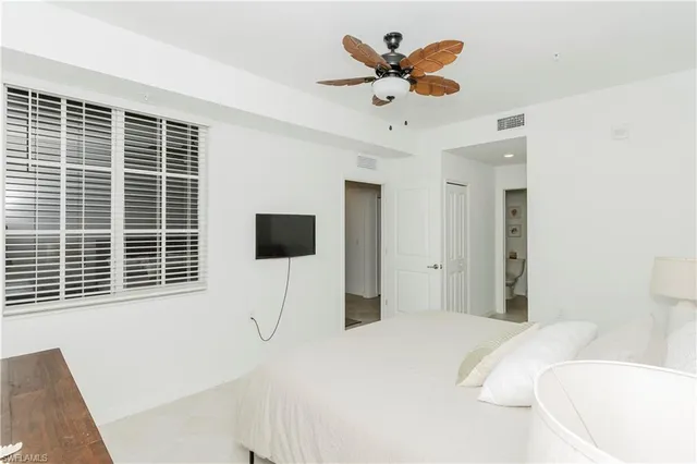 a bedroom with a bed a flat screen tv and a window