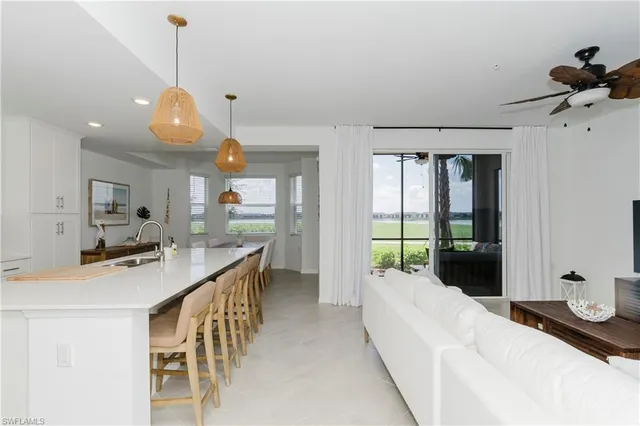 a kitchen with a sink a counter top space and living room view