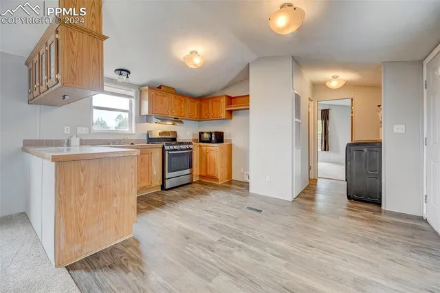 a kitchen with stainless steel appliances granite countertop a stove a sink and white cabinets with wooden floor