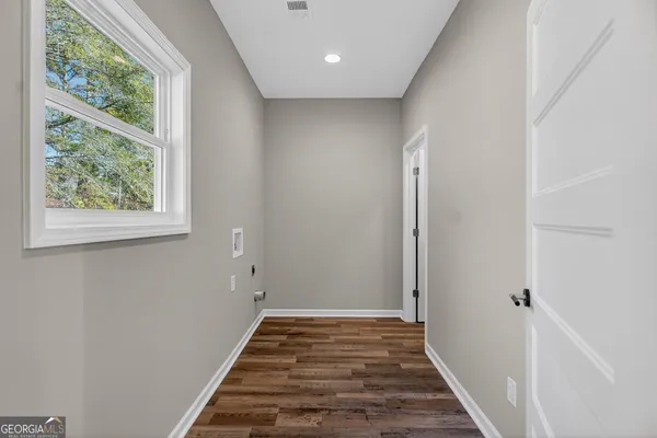 a view of a hallway with wooden floor and a window