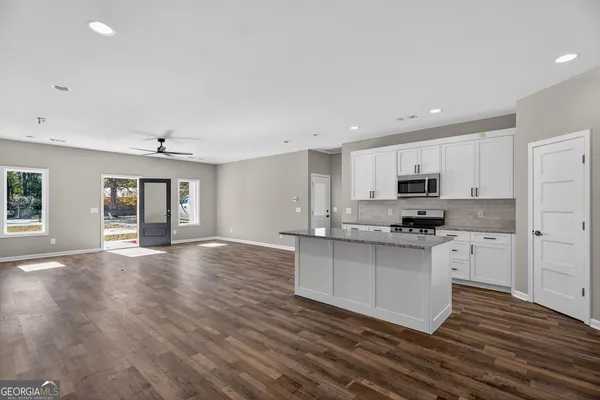 a kitchen with stainless steel appliances granite countertop a stove top oven a sink dishwasher and a refrigerator with wooden floor