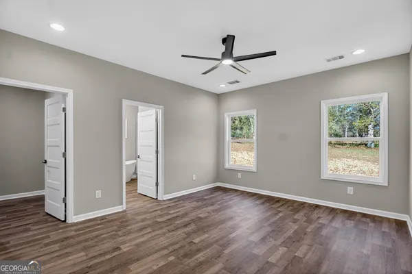 a view of an empty room with a window and wooden floor