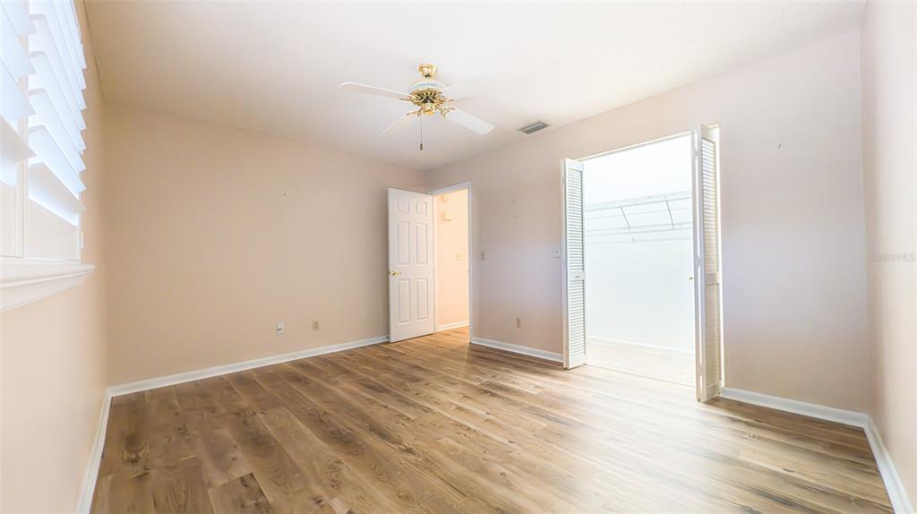 9357 Southwest 82nd Terrace, Unit C Ocala, FL 34481 - Photo 13 of 30 an empty room with wooden floor fan and windows