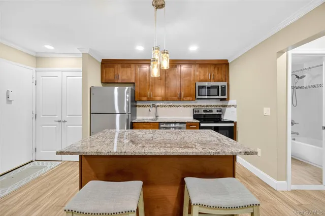an empty room with wooden floor and a kitchen