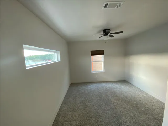 an empty room with windows and a ceiling fan view