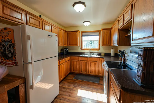 a kitchen with granite countertop a refrigerator a sink a stove and cabinets