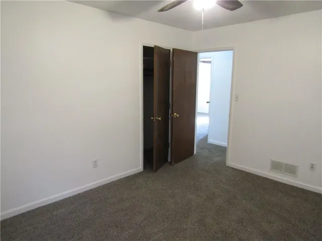 an empty room with closet and a chandelier fan