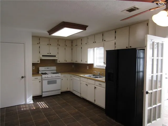 a kitchen with a sink a refrigerator and cabinets