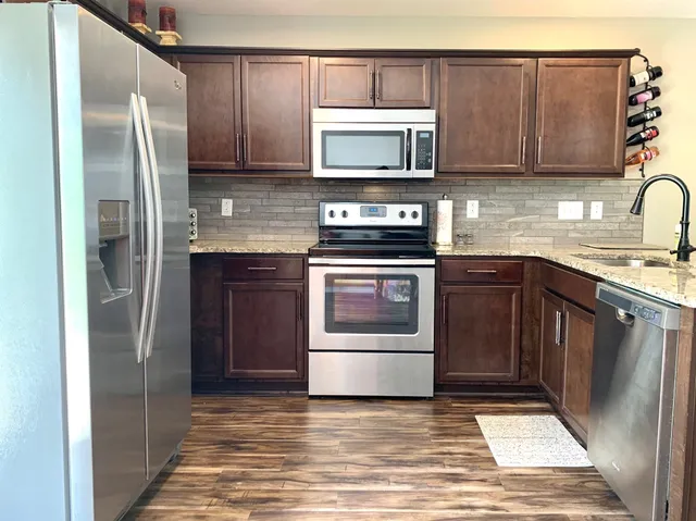 a kitchen with stainless steel appliances granite countertop a stove a refrigerator and a microwave