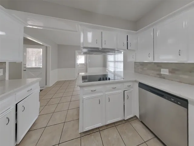 a kitchen with white cabinets appliances and a window