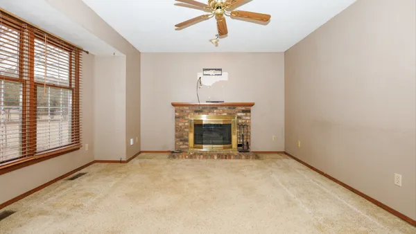 an empty room with windows and fan