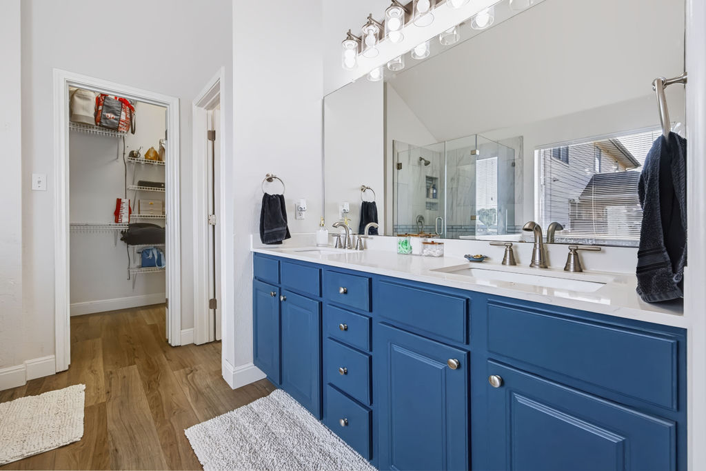 400 Ranier Lane Round Rock, TX 78665 - Photo 24 of 36 Double vanities with stone counters flank a spacious, modern bathroom layout featuring wood-patterned flooring.