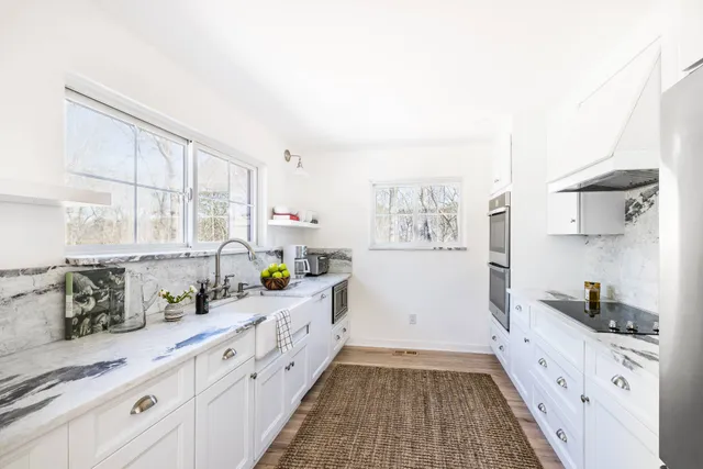 a large kitchen with stainless steel appliances a stove a sink and white cabinets