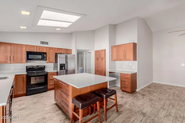 a large kitchen with stainless steel appliances a stove a refrigerator counter space and wooden floor