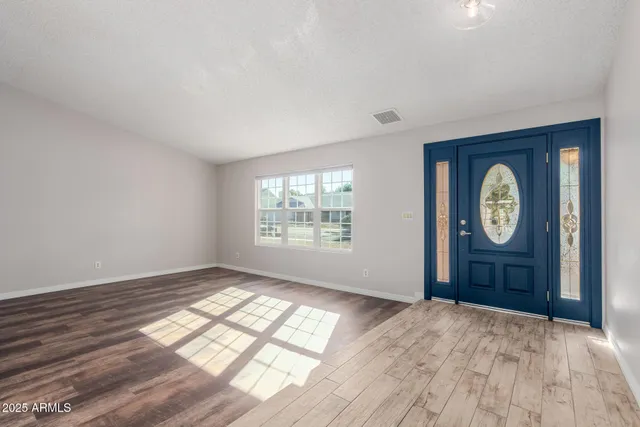 a view of an empty room with window and wooden floor