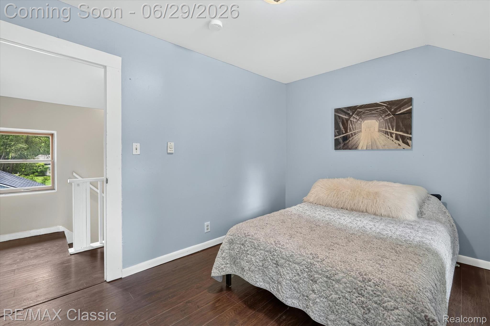 352 Meribah Road Highland, MI 48356 - Photo 20 of 39 Bedroom featuring wood-finish flooring, light blue wall paint, white trim, and a window with green outdoor scenery
