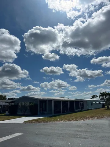 a view of swimming pool with lawn chairs and large tree