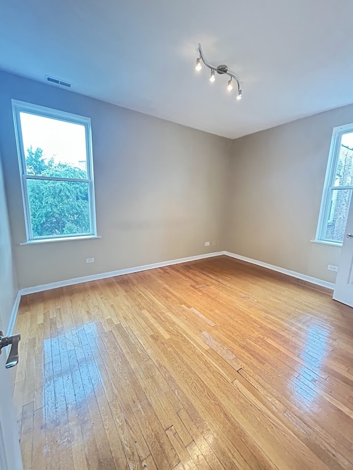 2052 East 68th Street, Unit 3 Chicago, IL 60649 - Photo 3 of 14 wooden floor in an empty room with a window
