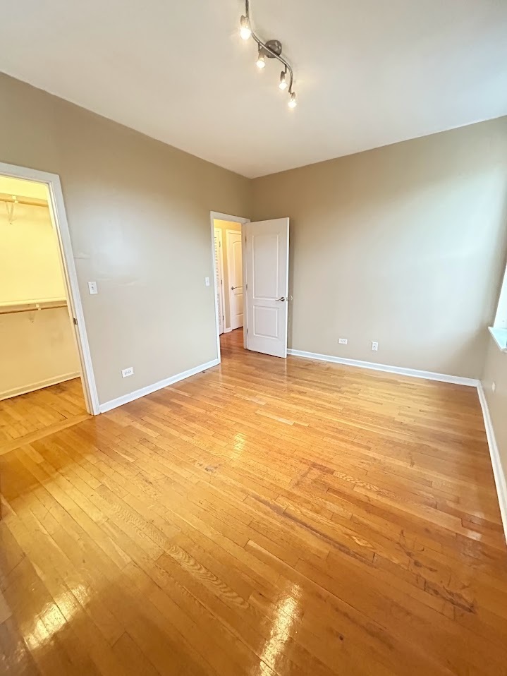 2052 East 68th Street, Unit 3 Chicago, IL 60649 - Photo 5 of 14 an empty room with wooden floor and windows