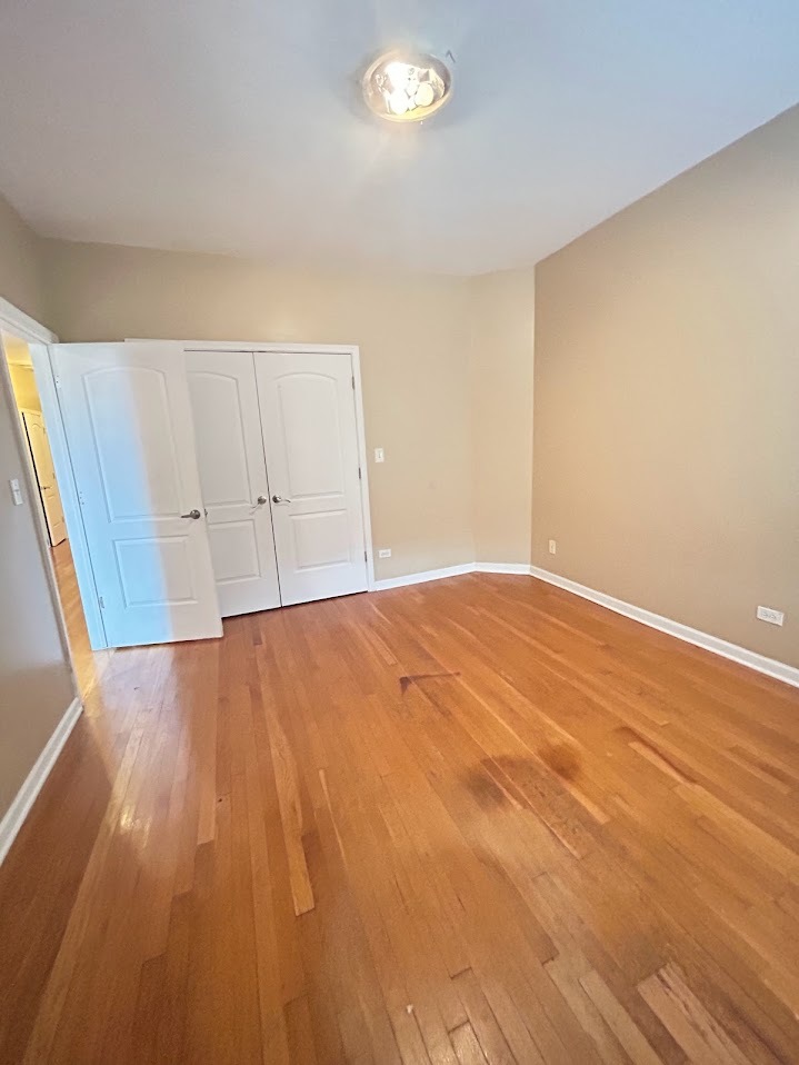 2052 East 68th Street, Unit 3 Chicago, IL 60649 - Photo 9 of 14 wooden floor in an empty room with a window
