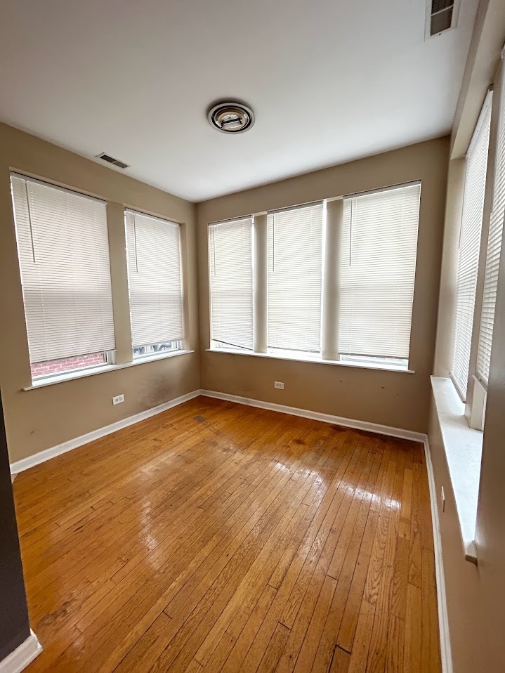 2052 East 68th Street, Unit 3 Chicago, IL 60649 - Photo 10 of 14 a view of an empty room with wooden floor and a window