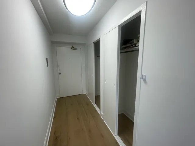 a view of a room with wooden floor and a small window