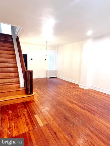a view of an empty room with wooden floor and stairs