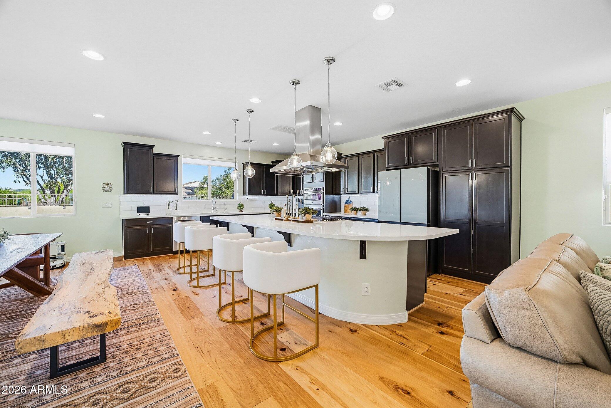 5819 South Wilson Way Gilbert, AZ 85298 - Photo 31 of 76 a kitchen with stainless steel appliances kitchen island granite countertop a refrigerator a stove a sink dishwasher and a dining table with wooden floor