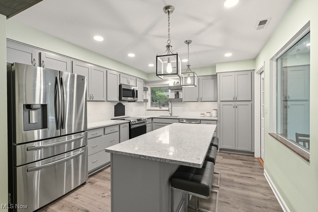 6753 Mill Road Brecksville, OH 44141 - Photo 5 of 34 Kitchen featuring stainless steel appliances, gray cabinets, hanging light fixtures, light stone countertops, and light wood-style flooring