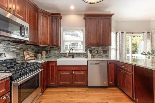 a kitchen with stainless steel appliances granite countertop a stove a sink dishwasher and a microwave oven with large cabinets