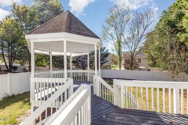 a view of a deck with large trees and wooden fence