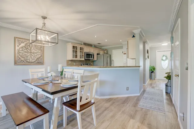 a view of a dining room and livingroom with furniture wooden floor a chandelier
