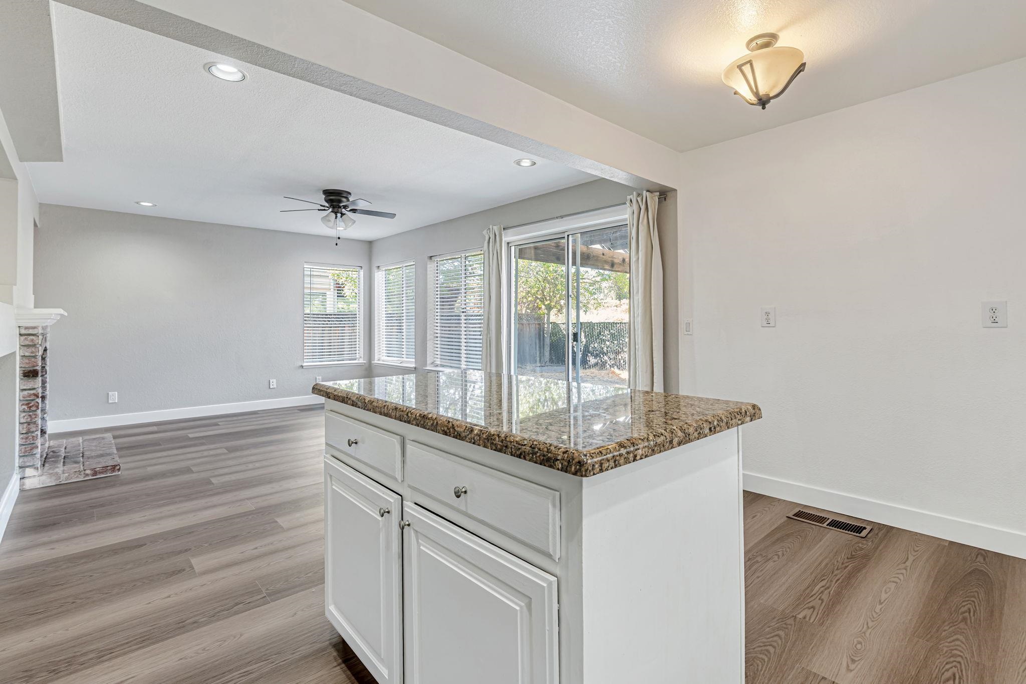 5052 Perry Way Antioch, CA 94531 - Photo 12 of 51 Kitchen with white cabinetry, dark stone countertops, light wood finished floors, a kitchen island, and a ceiling fan