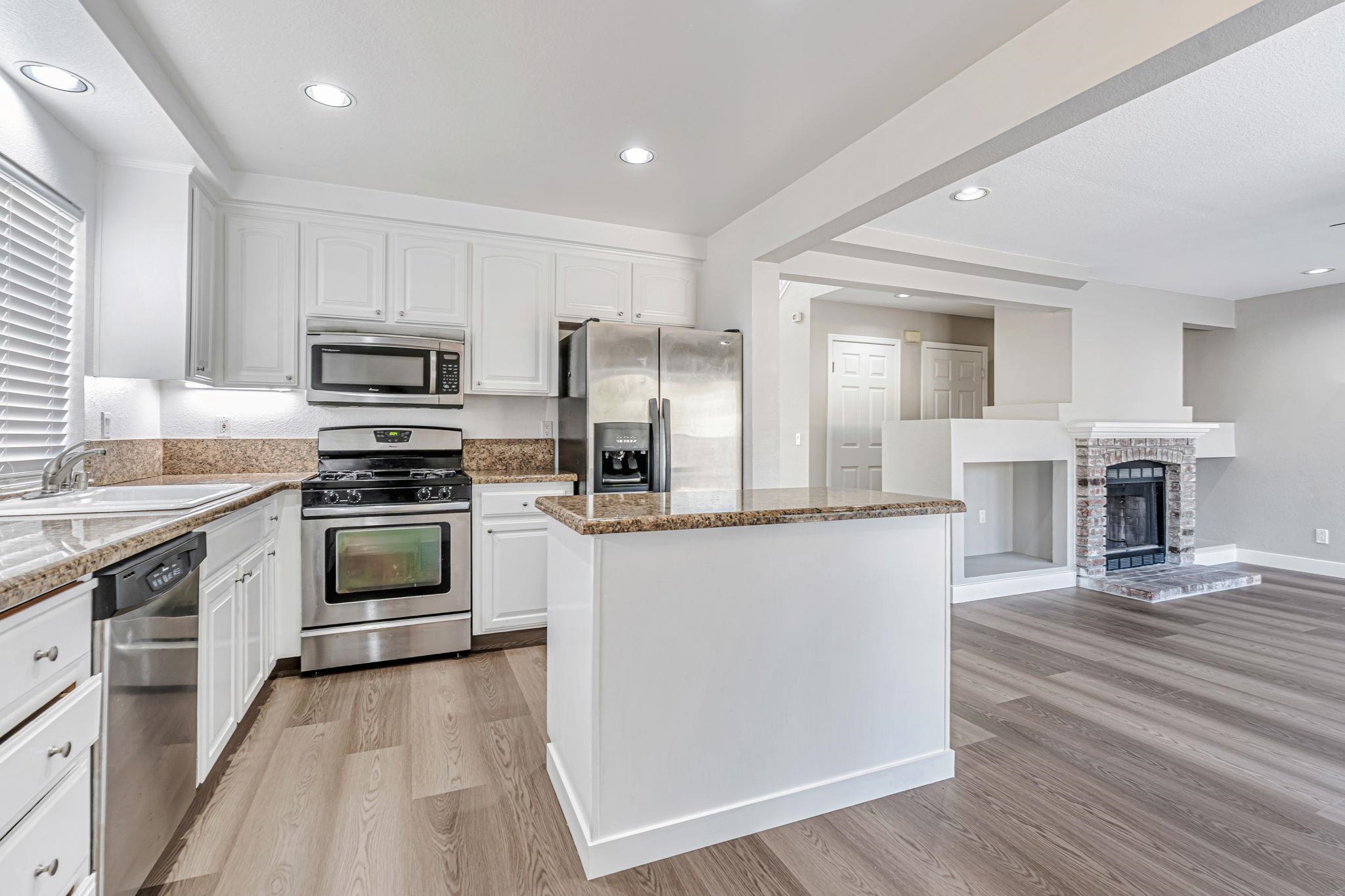 5052 Perry Way Antioch, CA 94531 - Photo 10 of 51 Kitchen featuring white cabinets, appliances with stainless steel finishes, a kitchen island, recessed lighting, and a brick fireplace