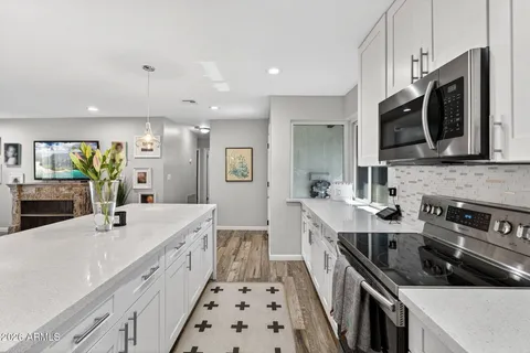 a kitchen with stainless steel appliances a sink a stove a microwave a center island and a window