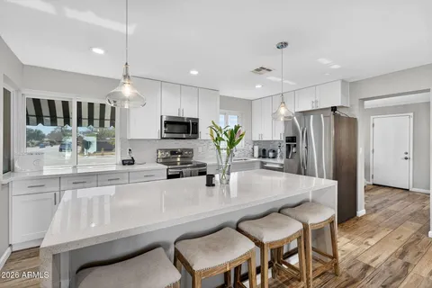 a large living room with stainless steel appliances kitchen island granite countertop a sink and cabinets
