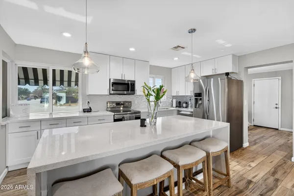 a large living room with stainless steel appliances kitchen island granite countertop a sink and cabinets