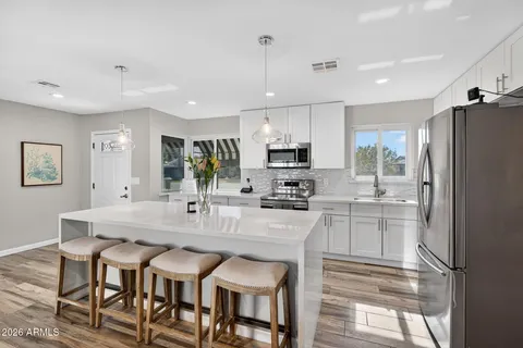 a kitchen with granite countertop a table chairs microwave and refrigerator