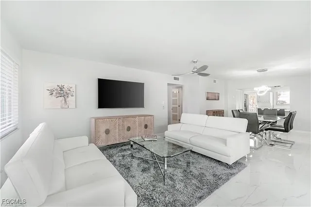 a living room with furniture a flat screen tv and white walls