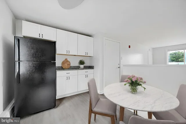 a kitchen with stainless steel appliances granite countertop a refrigerator a sink a stove a dining table and chairs