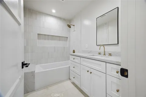 a bathroom with a double vanity sink a mirror and a bathtub