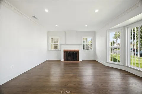 an empty room with wooden floor fireplace and windows